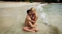 An image work full of art where a blonde short cut fierce beauty and a handsome man are intertwined naked on the beach!