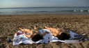 Two naked beauties frolicking on the beach