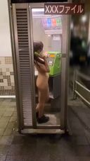 College girl is making a prank call to a stranger at a late night city phone booth