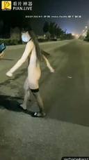 一個穿著裸領的剃光女人在城市裡漫遊並玩玩具